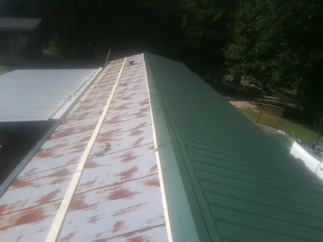 Old rusted panels beside newly installed green metal roofing — Wind Damage Roof Repair by Roofing Brothers in Nezperce