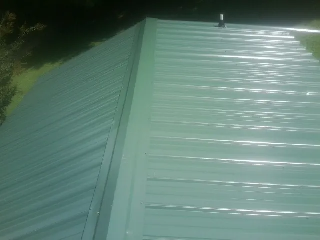 New green metal panels meeting at the ridge of a roof — Flat Roof Repair work by our crew in Nezperce