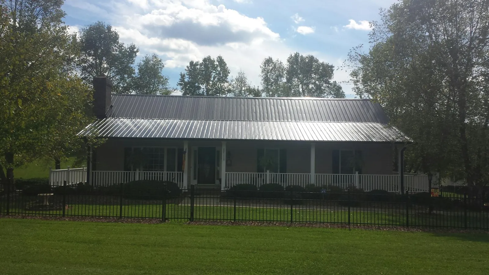 Gray metal roof on a brick ranch with a full width front porch — Gutter Guard Installation work by our crew in Nezperce