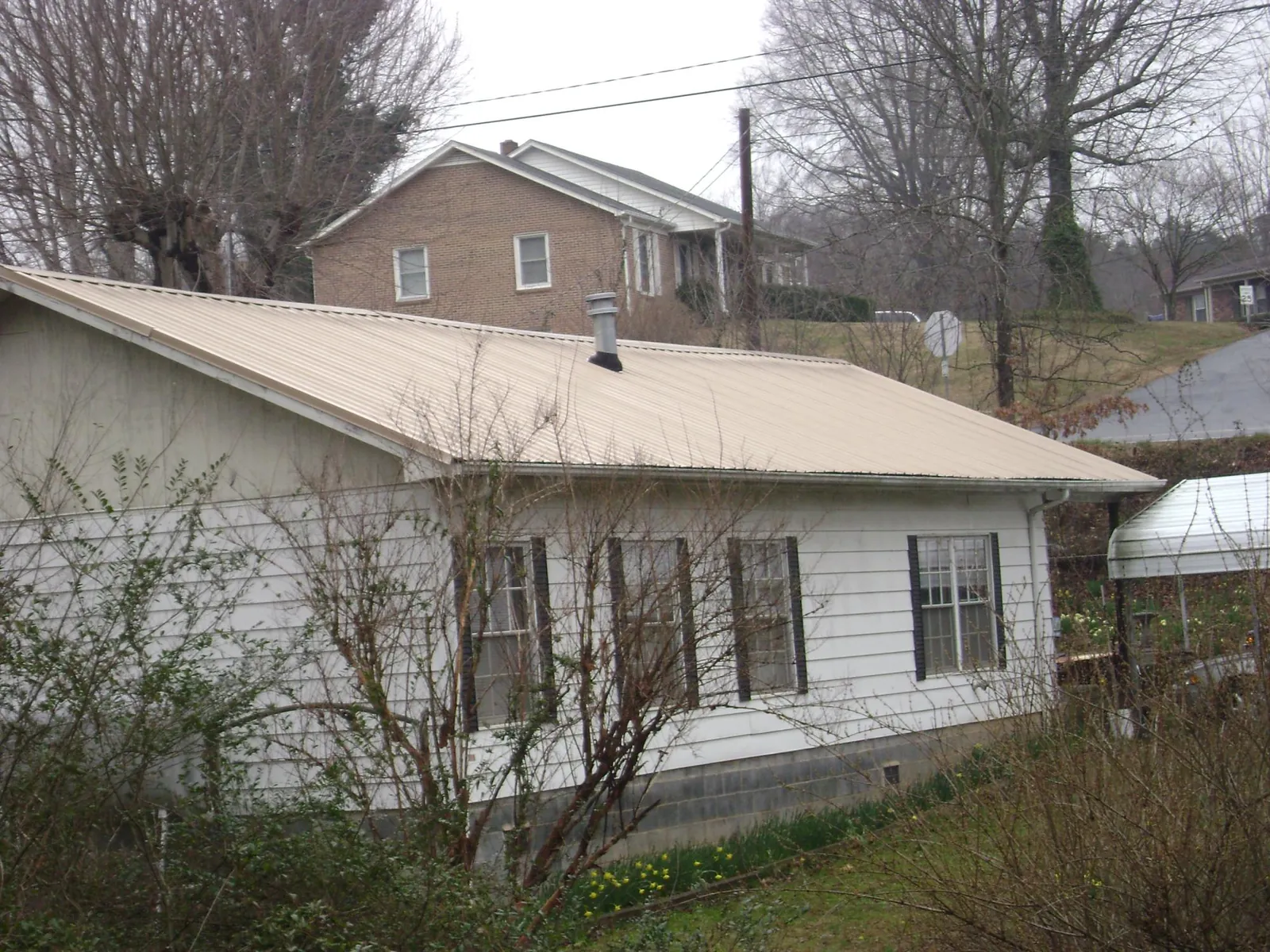 Tan metal roof on a white sided house set into a hillside — Commercial Roofing by Roofing Brothers in Nezperce