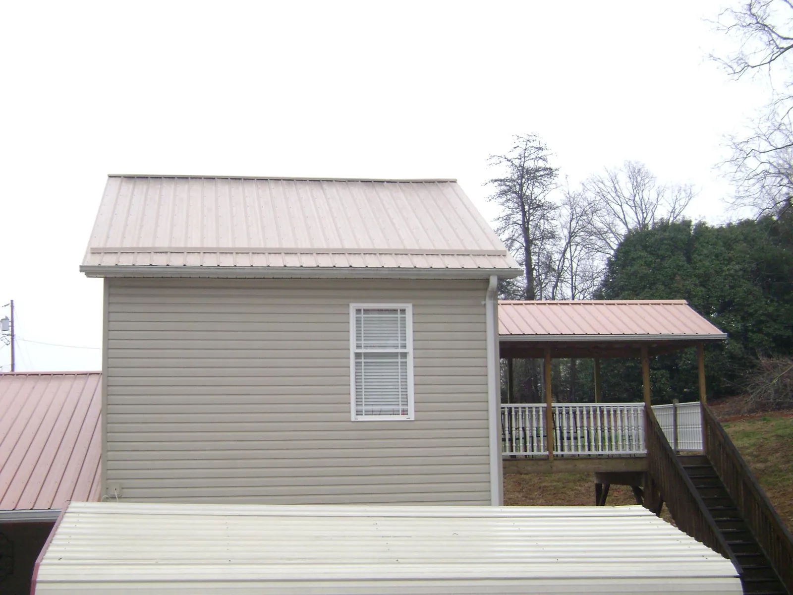 Tan metal roofs on a two story addition and attached porch, from a Roof Replacement job in Nezperce