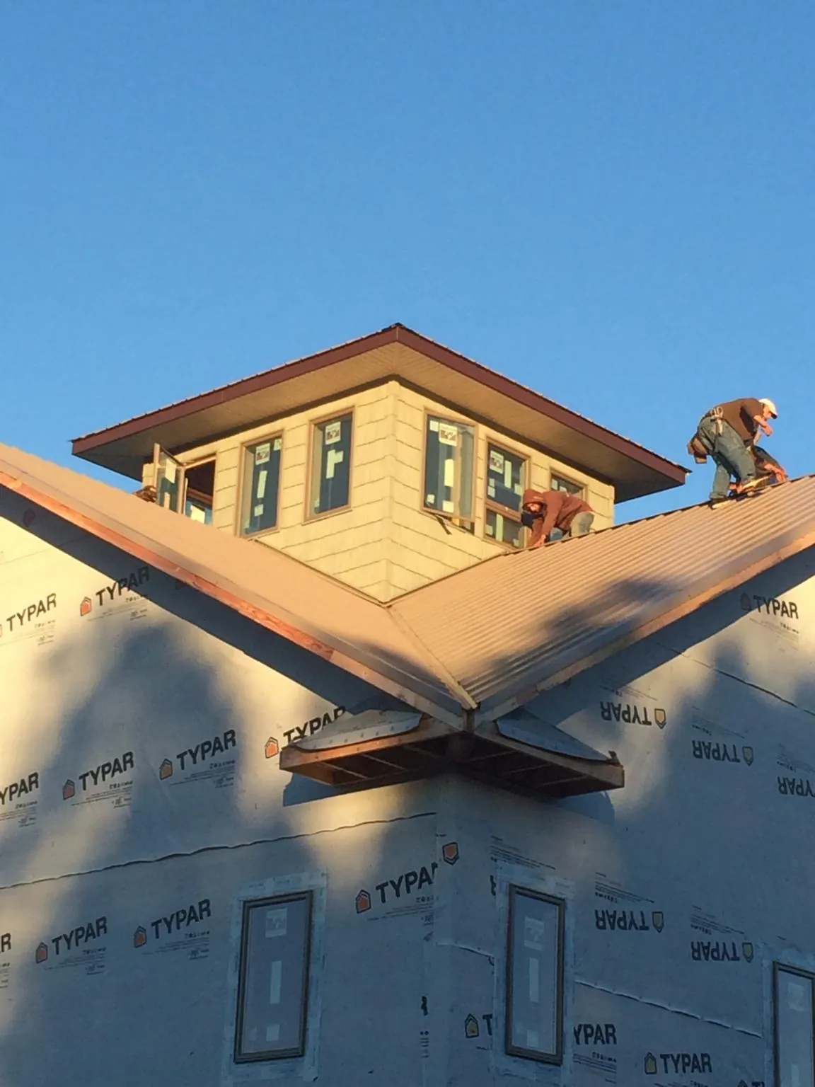 Roofers working around a rooftop cupola on a new metal roof at sunset — Roof Waterproofing in Nezperce by Roofing Brothers